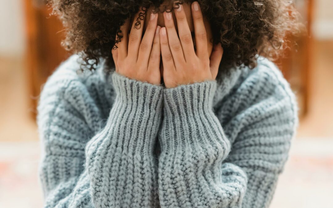 Personne assise en position fermée, regard vers le bas, illustrant un état d’amotivation ou de perte d’élan.